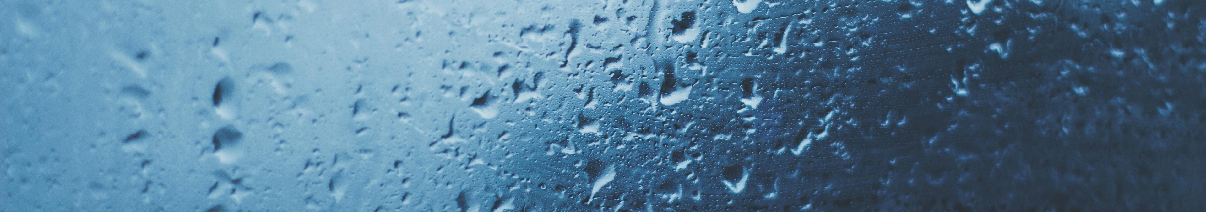 雨粒が窓ガラスに付着し、青いトーンで染まった風景